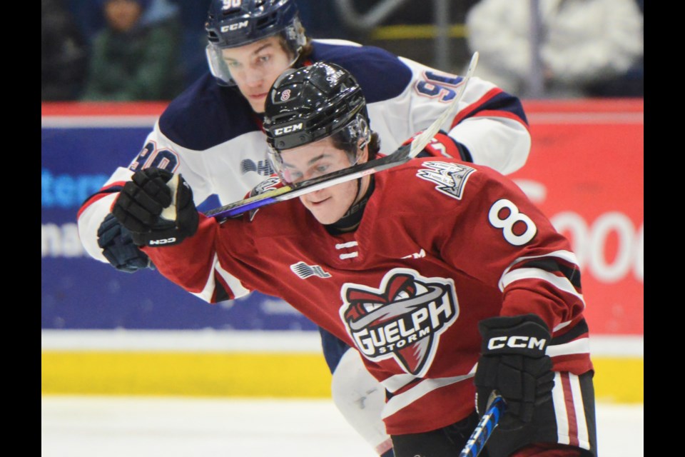 Guelph Storm forward Jesse FIshman takes a high stick from Saginaw's Luke McNamara Friday at the Sleeman Centre.