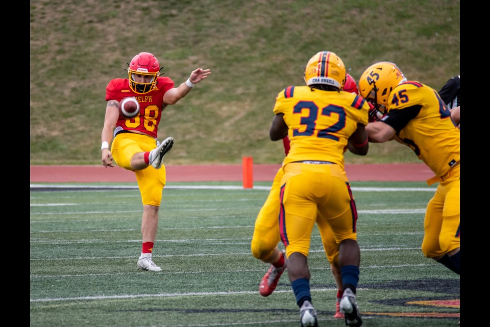 Nick Guardiero (88) of the Guelph Gryphons gets a punt away while a teammate holds off the Queen's Gaels duo of Emmanuel Ogunmefun (32) and Jacob Jefferies (45). Queen's won 62-11 in Guelph's Homecoming Game.