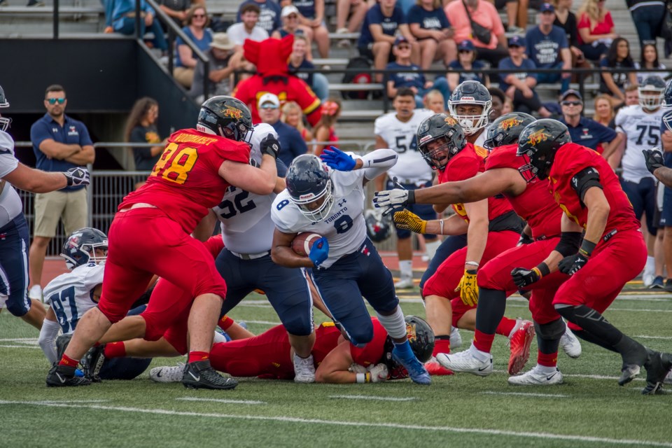 Running back Adam Williams (8) of the Toronto Varsity Blues tries to break through the defensive line of the Guelph Gryphons including Curtis Woodmansey during Saturday's OUA football game at Alumni Stadium. The Gryphons won the season opener 33-10.