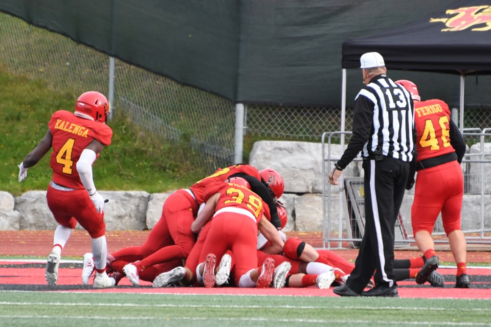 The Guelph Gryphons pile on Siriman Harrison Bagayogo after he blocked a punt and fell on the loose ball in the Carleton end zone Saturday at Alumni Stadium. Rob Massey for GuelphToday