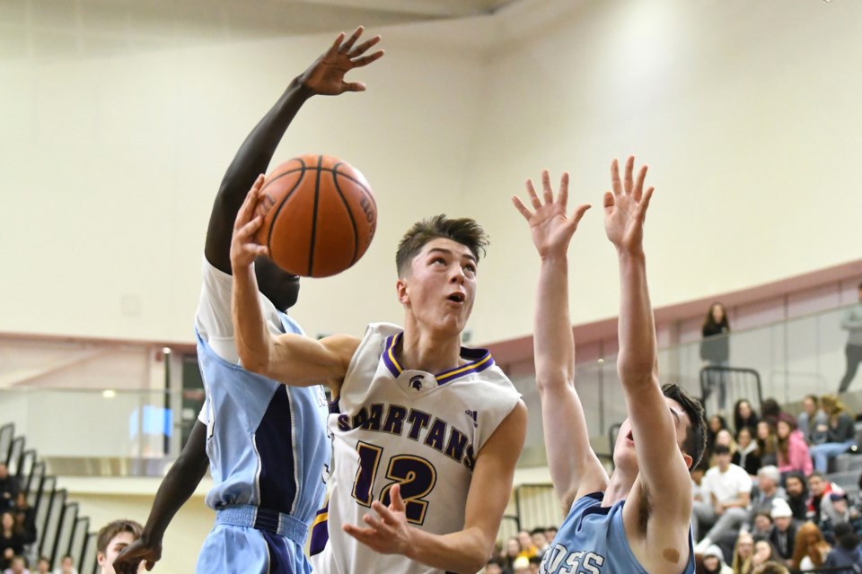 Jackson Wallace (12) of the Centennial Spartans heads to the basket between the Ross Royals pair of Gatlang Puot (left) and Cole Miller during Saturday's District 10 high school senior boys' basketball final at the Guelph Gryphons Athletic Centre. Centennial  won 72-61. Rob Massey for GuelphToday
