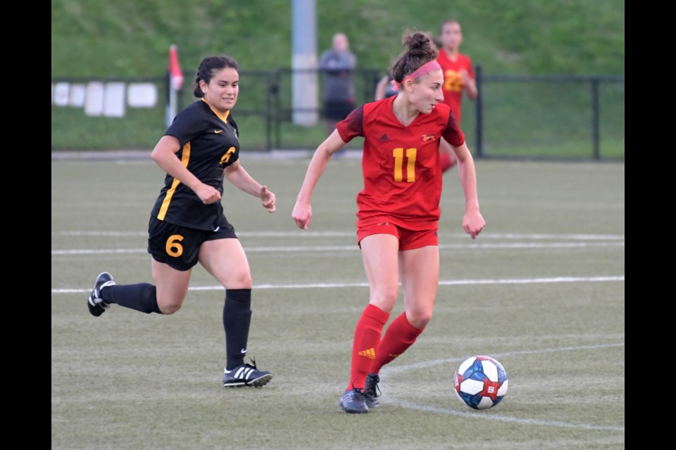 Midfielder Cloey Uddenberg (11) of the Guelph Gryphons carries the ball in front of a Waterloo Warriors opponent during Ontario university women's soccer play last month at the Gryphon Soccer Complex. Uddenberg was honoured as the top player in the OUA's West Division.