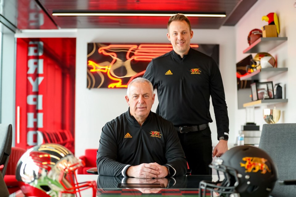 Surrounded by everything Guelph Gryphon football, Gryphon head coach Ryan Sheahan poses with his father Pat Sheahan after the elder Sheahan was named the offensive line coach and an offensive assistant on the team that has Ryan Sheahan as its head coach.