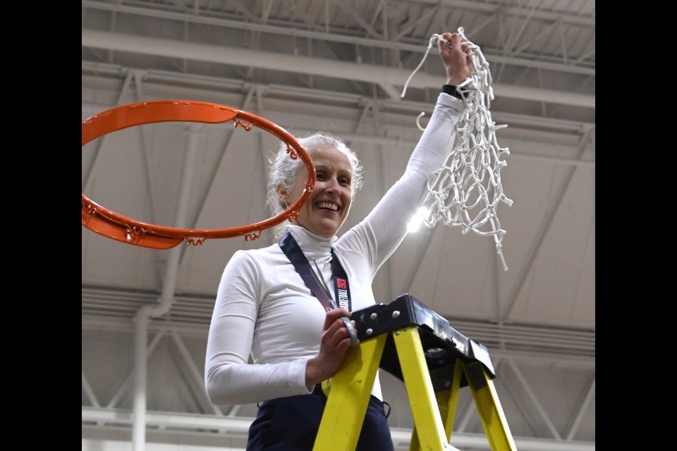 Guelph's Dani Sinclair, head coach of the Carleton Ravens women's basketball team, holds up the net after cutting it off the rim following her team's U SPORTS national championship win. It was her first national title as a head coach.