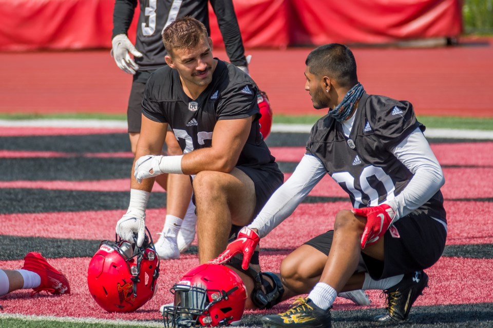 Guelph Gryphons veteran Simon Chaves, left, listens to a teammate during training camp at Alumni Stadium. The only player left with the team from his recruiting class, Chaves says he tries to answer all questions his young teammates might have about Gryphon football.
