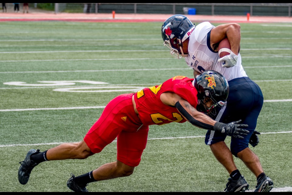 Devynn Cromwell of the Guelph Gryphons tackles a Toronto Varsity Blues opponent during 2023 OUA football play at Alumni Stadium. Cromwell could follow Tavius Robinson and Jaden Dicks as Gryphons who left the team to play NCAA football.