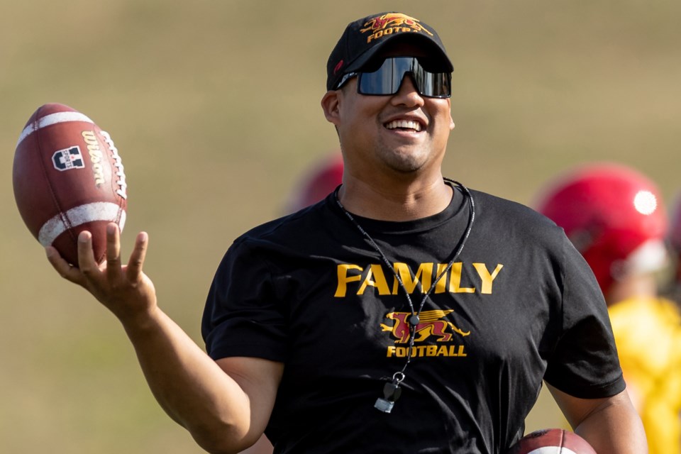 Mark Surya laughs as he holds a football aloft during the Guelph Gryphons football team's training camp in 2022. Surya was the team's offensive coordinator at the time and has been named the Gryphons head coach earlier this month.