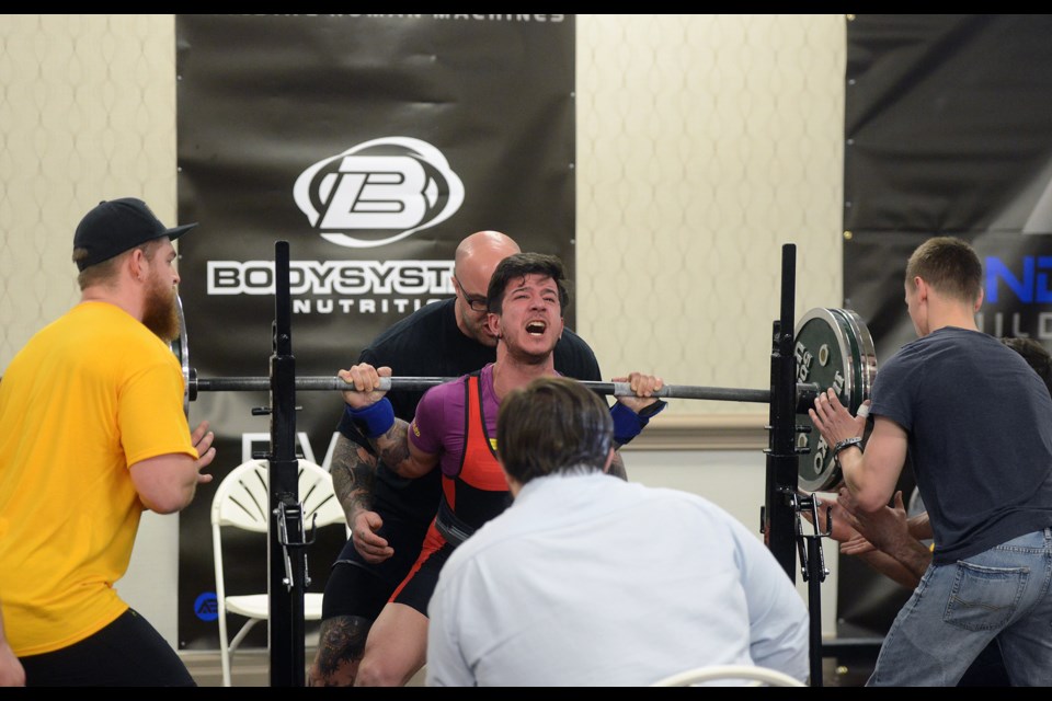 A judge watches intently and three spotters take up position during a squat attempt in the pro men's division. Tony Saxon/GuelphToday