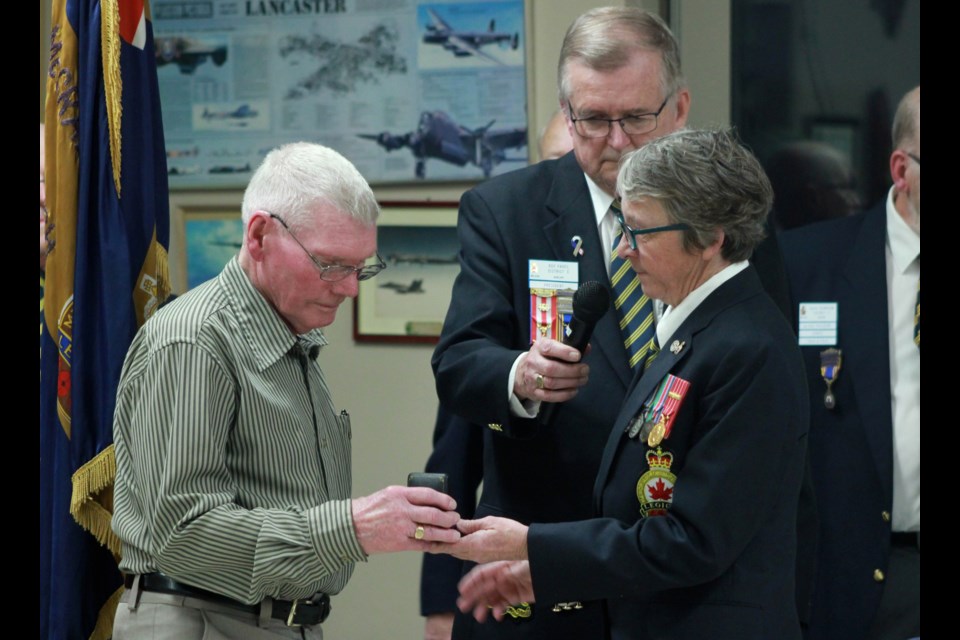 Susan Giebel hands the war medal to George Cook. Anam Khan/GuelphToday