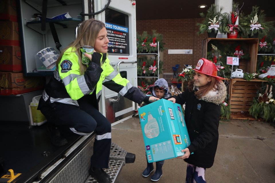A girl giving a box of diapers for the food bank at the Stuff an Emergency Vehicle event Saturday at the Paisley Road Zehr's location.