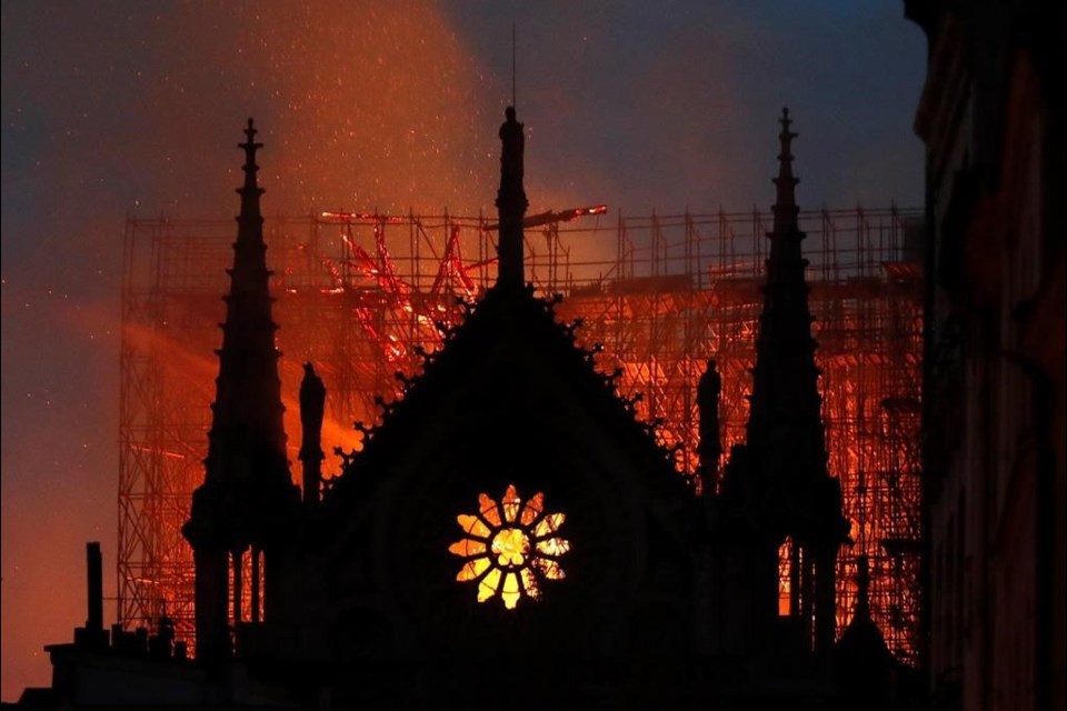 Flames and smoke rise from Notre Dame Cathedral as it burns in Paris, Monday, April 15, 2019. Massive plumes of yellow brown smoke fill the air above Notre Dame Cathedral and ash fell on tourists and others around the island that marks the centre of Paris. (AP Photo/Thibault Camus)