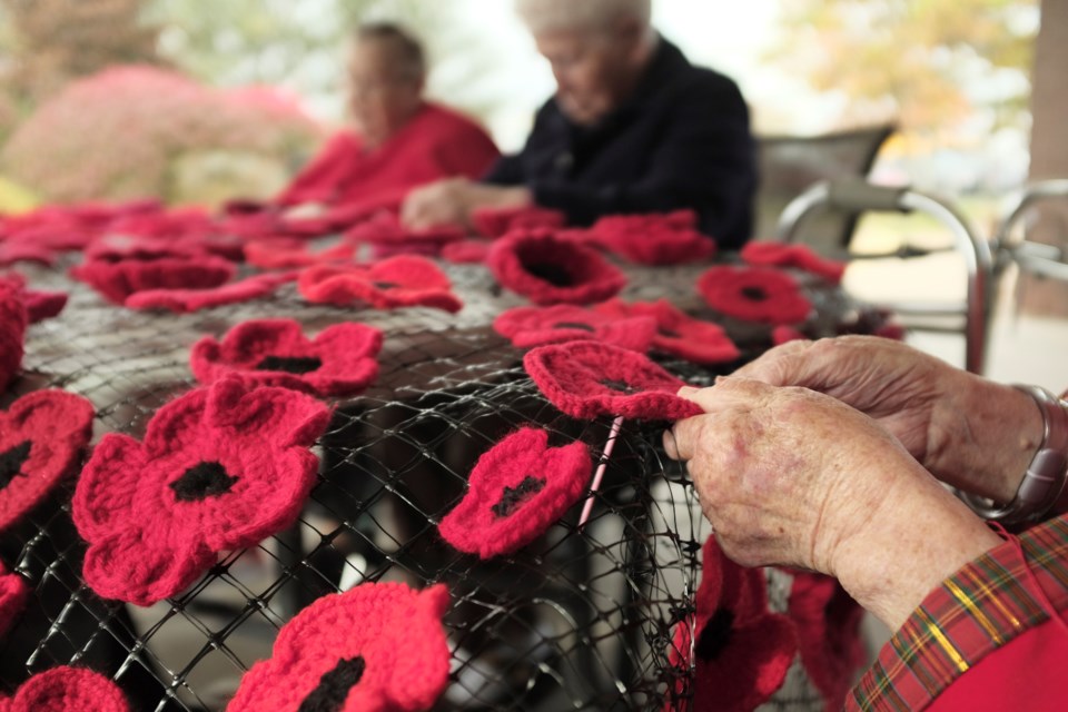 A resident of Oakwood Terrace works on the knitted poppy display. 