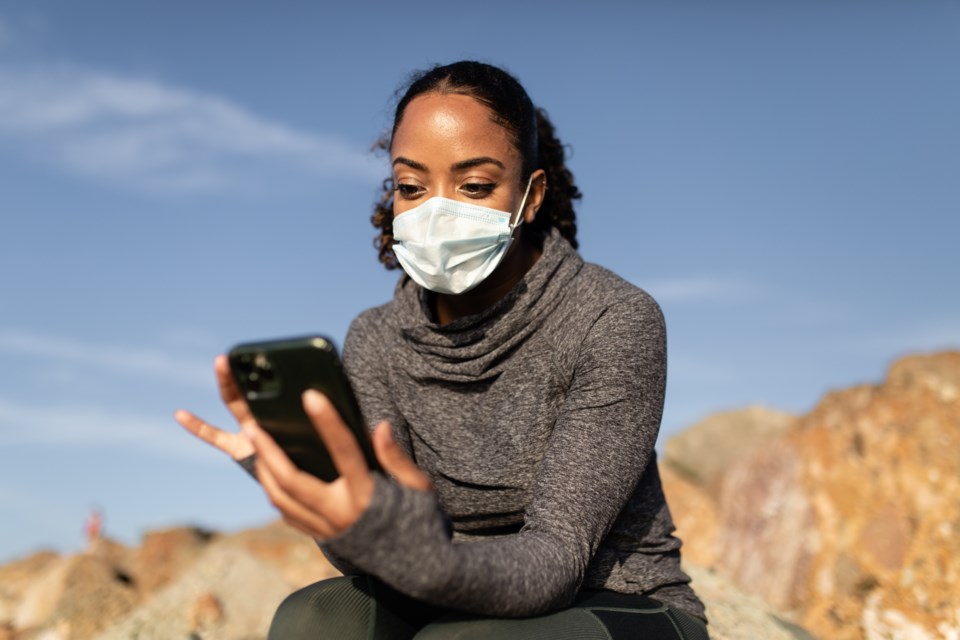 woman wearing mask holding phone