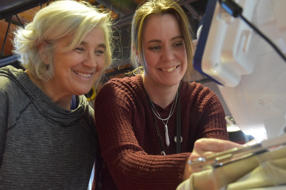 Barrie resident Lisa Foreman, left, and creative making and discovery programmer Rachel Martin use an embroidery machine at the HackLAB. 