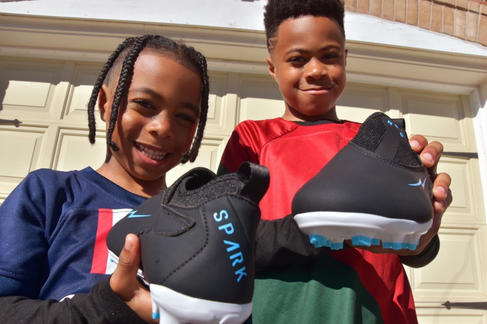 Tyler Khan, 8, and his brother, Taysen, 5, hold a pair of NRG soccer cleats.