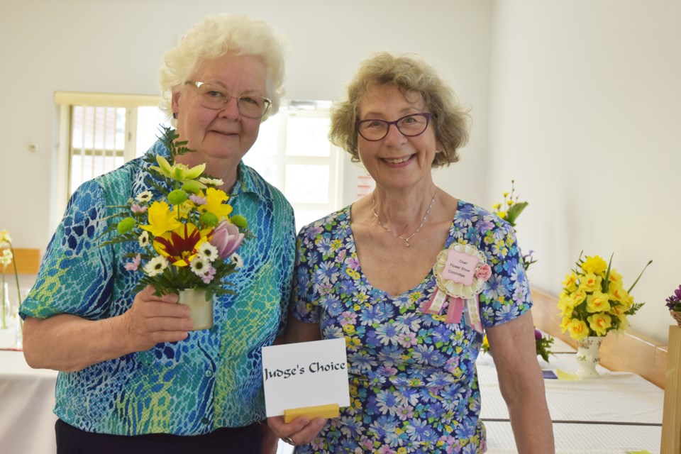 Jenni Murrell, Chair of the Flower Show Committee, at right, congratulates Jan Drybrough, whose flower arrangement 'Burst of Spring' won Judge's Choice.