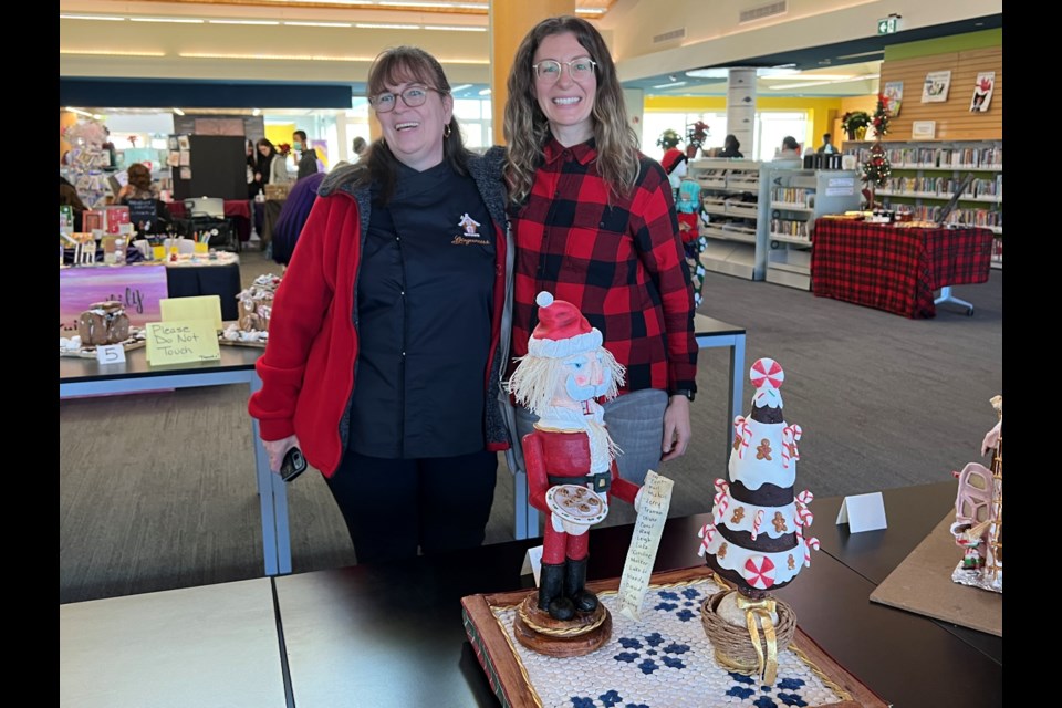 Beatriz Muller (left) and Christina, the first-place winner (adult) of Simcoe County's annual Gingerbread House Contest, with Christina's show-stopping piece that defies gravity. 