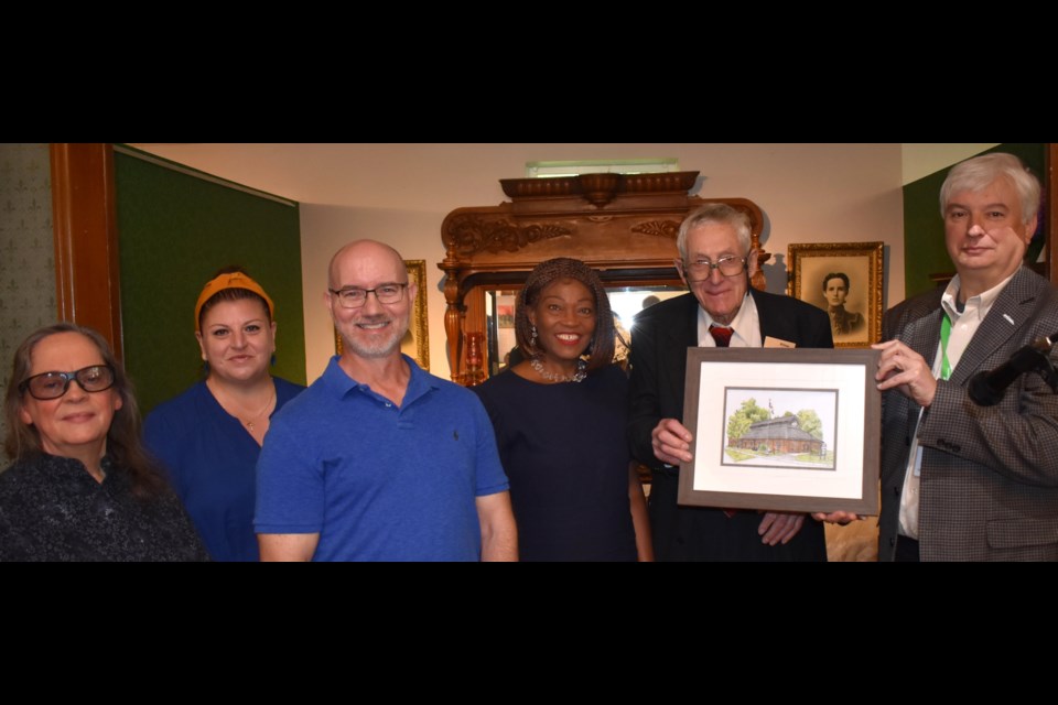 William Kell with Coun. Grace Constantine and friends. Kell is holding a painting of the museum, which was gifted to him by the Wall of Honour selection committee.