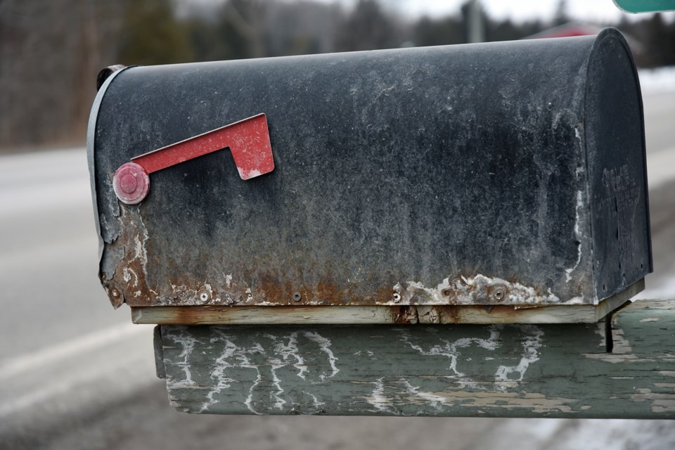 Old-fashioned utilitarian mailbox, rusted and weather-beaten still gets the job done.