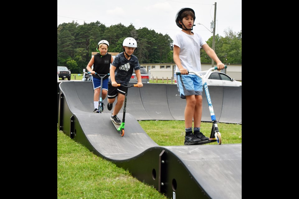 Youngsters ride scooters to try out the BMX pump track at Innisfil Beach Park after the ribbon was cut to official open the new amenity.