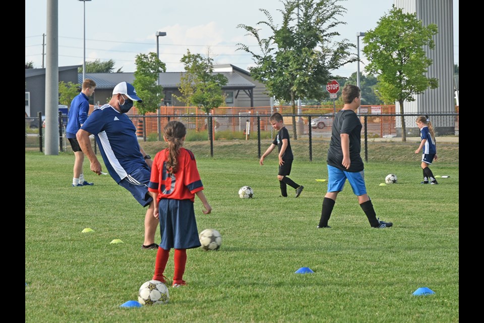 At left, Technical Director David Thorburn demonstrates a kick for U6 players. Miriam King/Innisfil Today