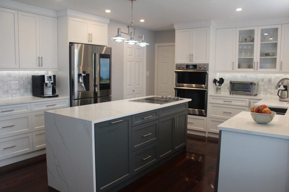 A completed kitchen renovation by Magnum Construction, including new cabinets, tiles, waterfall countertop, paint and design. 