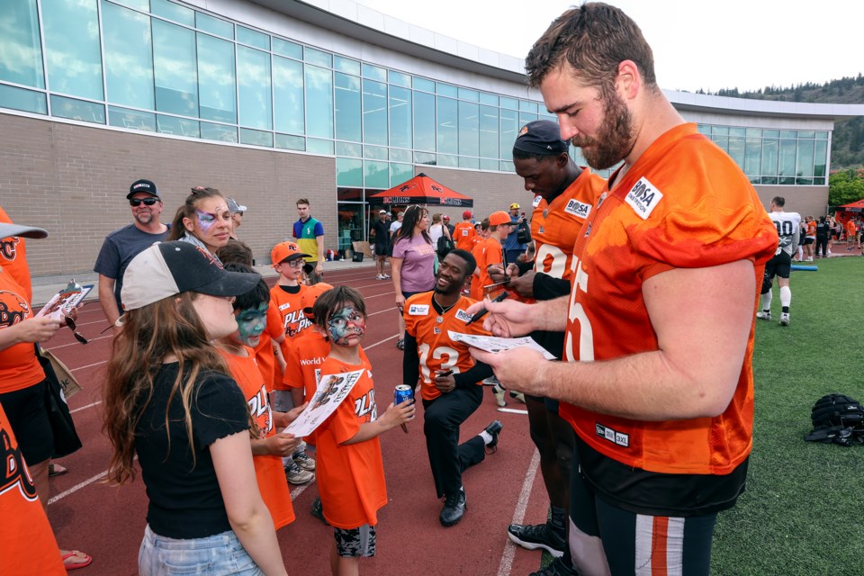 BC Lion Dominique Rhymes (left), Xavier Williams and Noah Zerr sign autographs for young fans.
