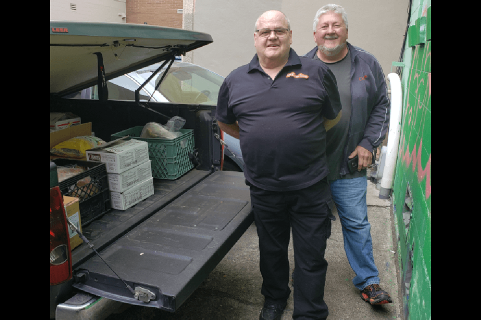 Gerald Thiessen of Papa G’s Cafe has 
helped many groups, including The Pit Stop, 
where here he donates a truck load of food to 
Rick Windjack of the meal-serving organization.

