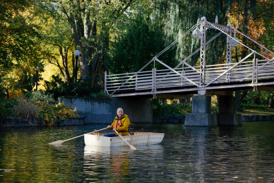 Matt Morris (Nov. 1st, 2021) in the boat he designed and built as a "pandemic project". To the best of his knowledge, it is the world's first three-part nesting skin-on-frame rowboat. It weighs 36lbs, and he gets it to the lake by towing it behind his bicycle. Matt decided to tackle this project after seeing a sign by Victoria Park Lake that proclaimed that boating was allowed. 