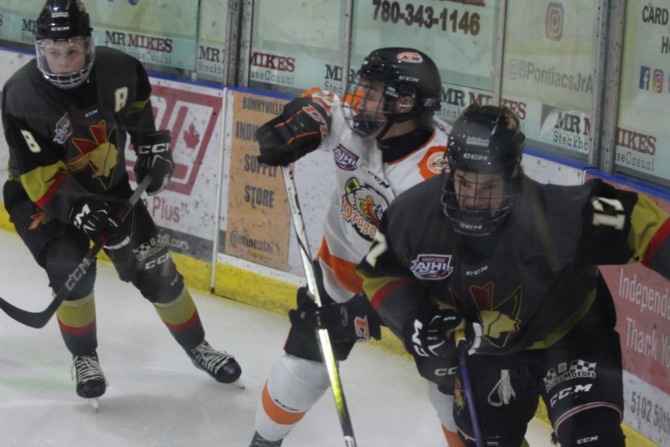 Pontiacs forward Tyler Blocha and defenseman Pier-Olivier Allard race to the puck against Drumheller Dragons defenseman Ben Christian.