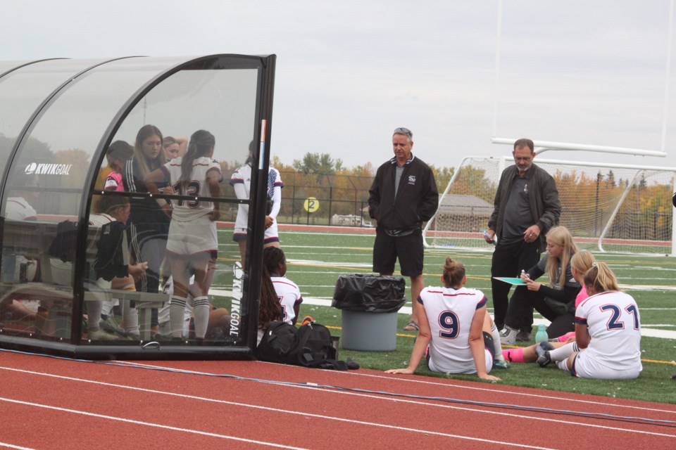 Al Bertschi, who recently replaced Kika Mukuninwa  as head coach of the Portage College men's and women's soccer teams, along with assistant coach Allan Robertson, go over some game strategy with the women's team at halftime. Chris McGarry photo. 