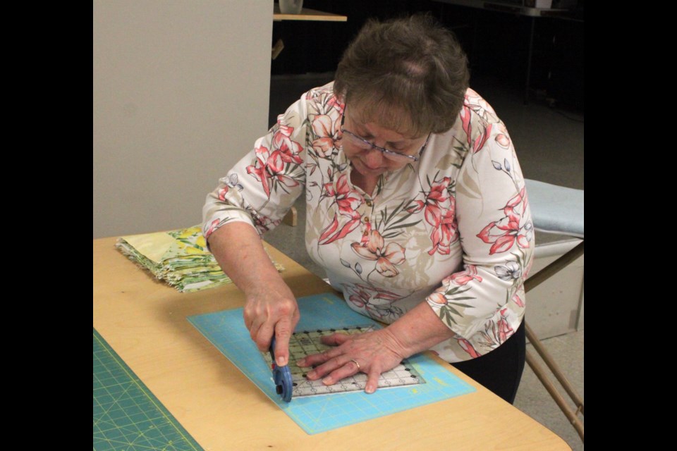 Annemarie Diachinsky squares off blocks of fabric to be made into a quilt at the quilting, sewing, knitting, and crocheting event, which took place at the Lac La Biche Heritage Society on March 22. Chris McGarry photo. 