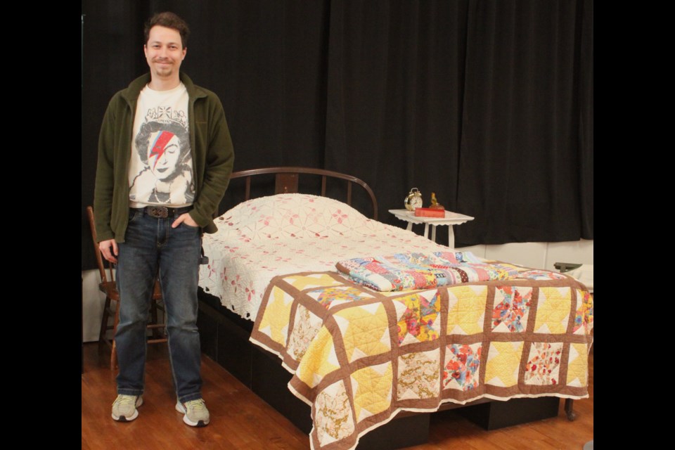 Artemii Plekhanov, an employee of the Lac La Biche Regional Museum, stands next to a diorama of a bedroom featuring vintage and antique quilts as part of the Timeless Comfort: Quilts and Blankets exhibit. Chris McGarry photo. 