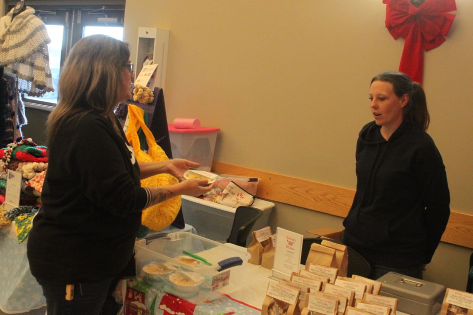 Lac La Biche County Baker Ashley Hill owns Krarups Kitchen. Her cakes, cookies, cheesecakes and delectable sweets can be found at local markets, including the most recent Christmas Farmer's Market that took place Friday at the Lakeland Agricom. Hill has a chat with Kathy Minard, who stopped by to purchase some of her sweets. Chris McGarry photo. 