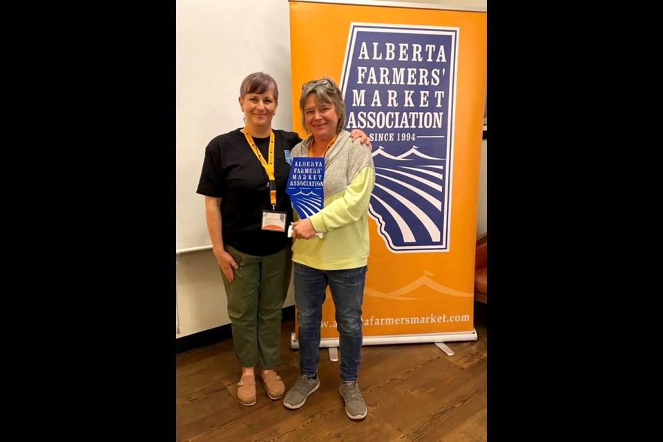 Bev Tkachuk, who is the manager of the Lac La Biche Farmer’s Market, was recently presented with the Outstanding Market Manager of the Year Award during a ceremony held by the Alberta Farmers Market Association (AFMA) in Red Deer. Tkachuk, right, stands next to Christie Fleck, AFMA business manager. Submitted photo. 