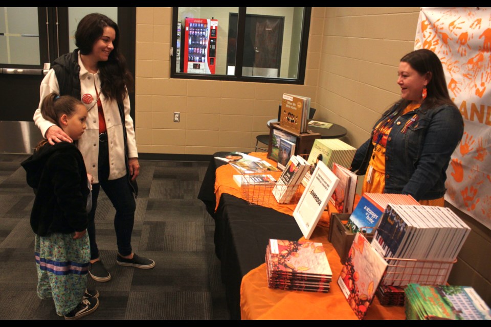 Valerie Griggs and her daughter, Naomie Cloetens peruse a table holding various books with stories about the residential school system and those who experienced it. Standing behind the table is Chantal Sparklingeyes. Chris McGarry photo. 