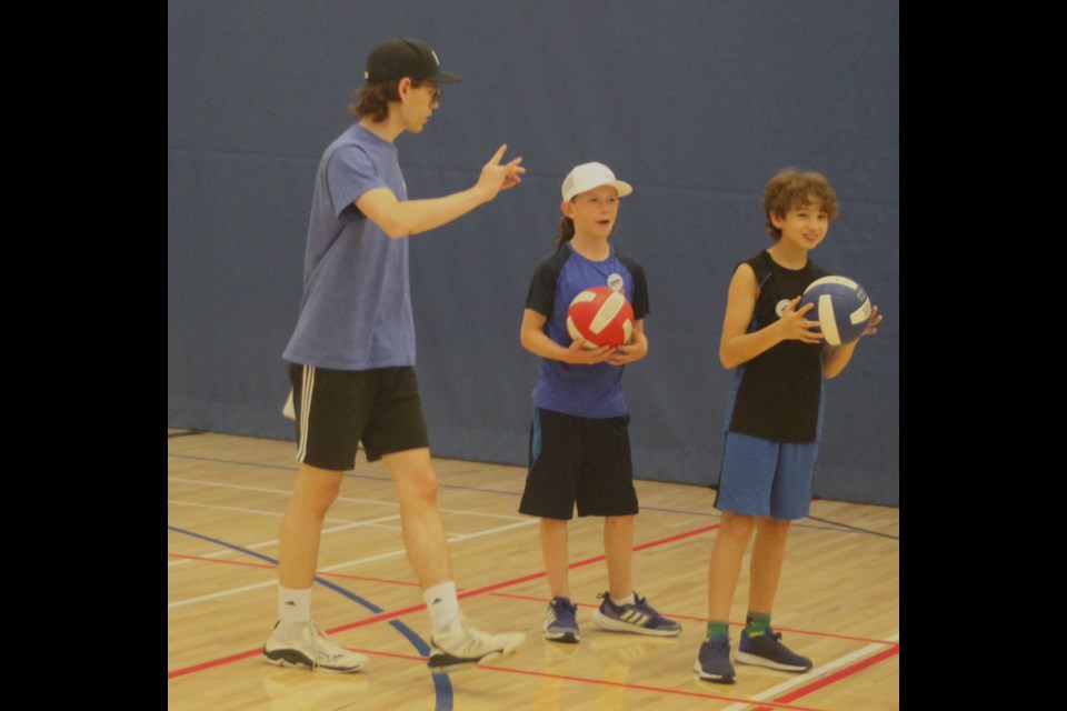 Braden Reid gives some advice to Brayden Pelkey and Krew McKay during a passing drill. Chris McGarry photo. 