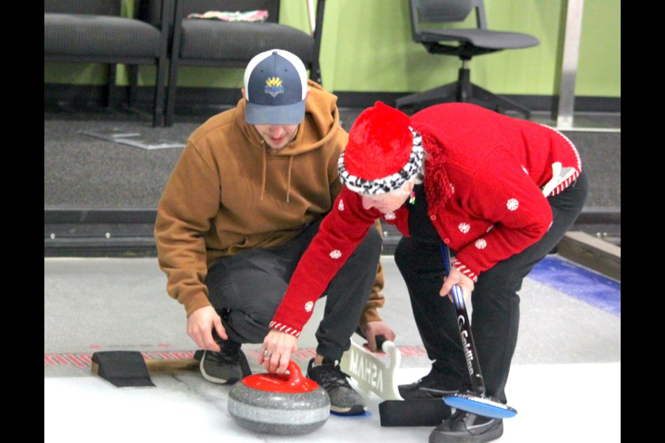 Brenda Robitaille of the Lac La Biche Curling club shows Nick Berziuk how to throw a rock during the Christmas Fun Friday Night event that took place on Dec. 15. Chris McGarry photo.