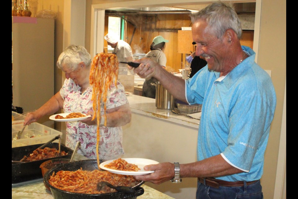Doug Marchesi and his sister, Margaret, scoop up some of chicken cacciatore onto their plates at the Venice Picnic, which has been taking place in the community since 1946. The 2025 edition of the event was held on June 1 at the Venice Heritage Park. Chris McGarry photo. 