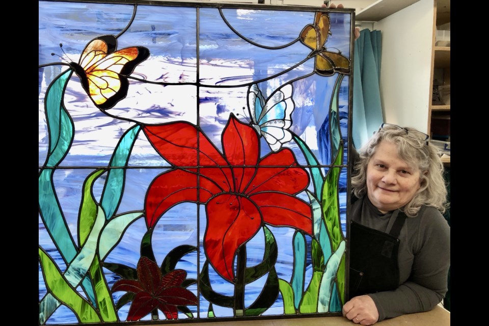 Noella Somerville stands with one of her pieces of stained glass art, containing butterflies and tigers. / Submitted photo. 