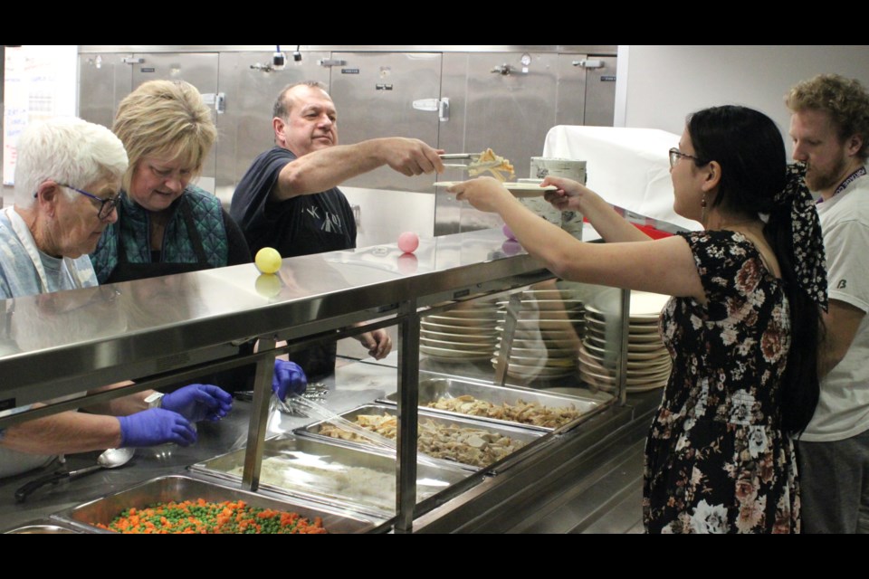 Colin Cote, a congregant at Lord of Glory Lutheran Church, serves up some food to Louisa Bone. Chris McGarry photo.