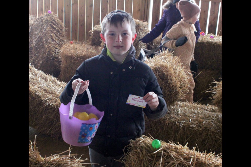 Corbin Buller proudly stands with the basket full of Easter eggs he’d collected during the hunt and holds up his passport, which enabled those who attended the party to access all the events taking place inside the pavilion. Chris McGarry photo.