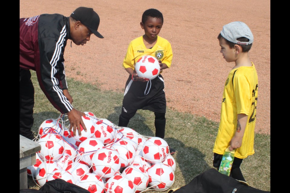 Emmanuel Lord, an assistant coach with Lac La Biche FC, hands out balls to players from a large bag at Soccerfest. Chris McGarry photo.