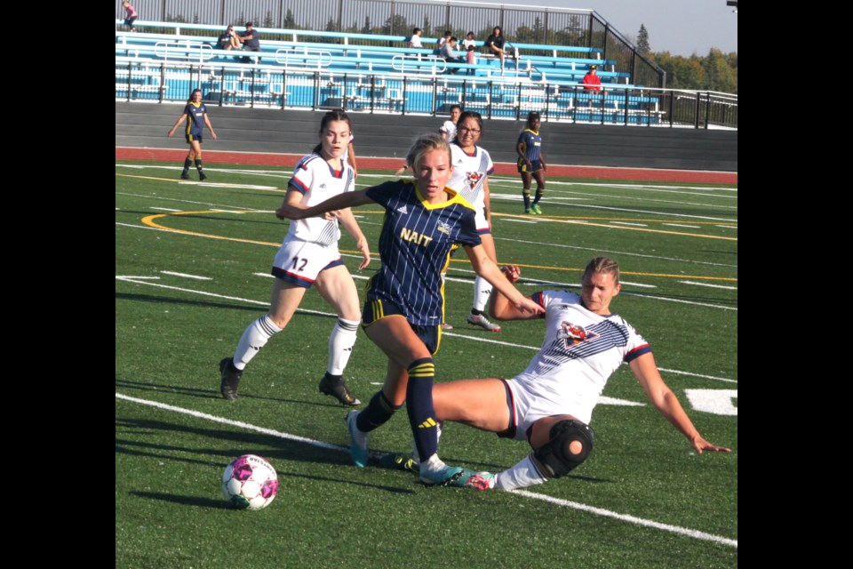 Portage midfielders Ashley Tether (right) tries for a slide-tackle on Ooks midfielder Ally Martineau as Voyageur teammate Brooklyn Haub approaches. 