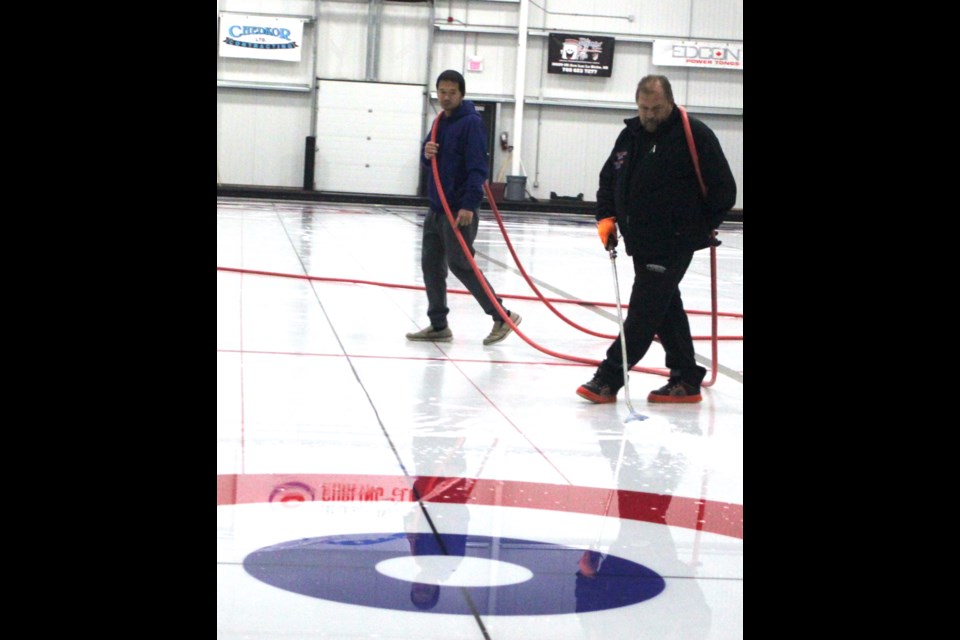 Kevin Grumetza of Hack to Hack Solution Inc.. and Justin Segura of Lac La Biche County walk back and forth as they flood the ice surface of the curling rink at the Bold Centre Tuesday as part of the process of getting the ice ready for the upcoming season for the Lac La Biche Curling Club, which starts on Oct. 20. 