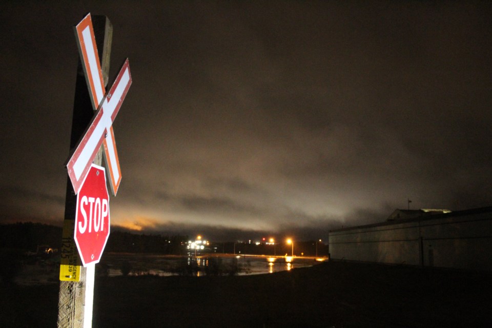 Fears that water pushing through railway infrastructure could cause severe flooding has closed roads and forced evacuations in Lac La Biche County. Here, Monday morning's low storm clouds hang over the flooded potion of Highway 55 alongside the railway tracks.      
Image: Rob McKinley
