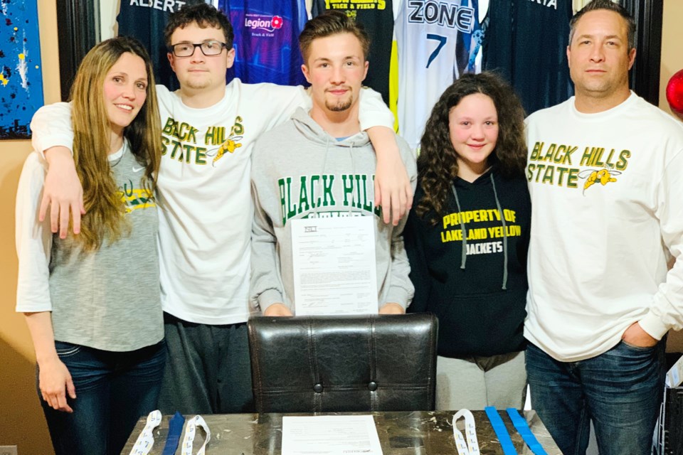 Mason Sartain (centre) signed his commitment to Black Hills State University alongside his family. Photo submitted. 