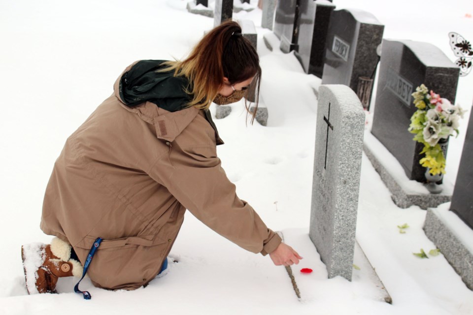 Grade 12 student Alias Skarsen places a poppy on a fallen soldier's grave. Photo by Robynne Henry.
