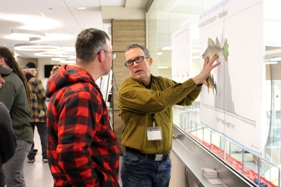 During the Alberta Environment and Parks fisheries management open house at the Cold Lake Energy Centre on Monday, Jan. 20, Dwayne Latty (right), senior fisheries biologist, and Cold Lake resident Vernon Miller discuss the number of eggs produced by larger females versus smaller female fish. Photo by Robynne Henry. 