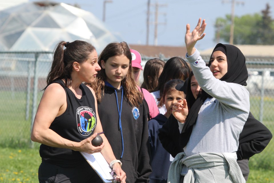 Aurora teacher Monique Ulliac shows student Lana Kabalan the proper shotput technique during practice throws at Thursday's school track and field day